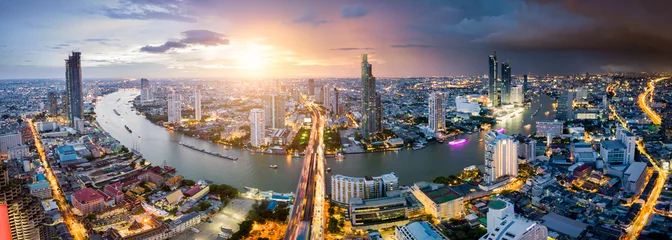 Fototapeten Luftaufnahme der Skyline von Bangkok und des Wolkenkratzers mit Lichtspuren am Geschäftszentrum der Sathorn Road in der Innenstadt von Bangkok. Panorama der Taksin-Brücke über den Fluss Chao Phraya Bangkok Thailand bei Sonnenuntergang. © Travel man
