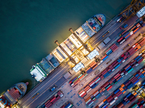 Top view of international port with Crane loading containers in import export business logistics at night.