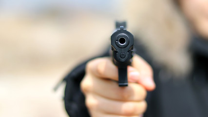 Woman&nbsp;pointing&nbsp;a&nbsp;gun&nbsp;at&nbsp;the&nbsp;target&nbsp;on&nbsp;soft&nbsp;background.