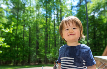 Young toddler boy playing with water from a garden hose outside