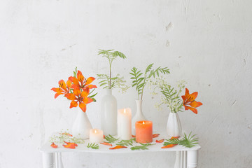 forange flowers and candles on white background