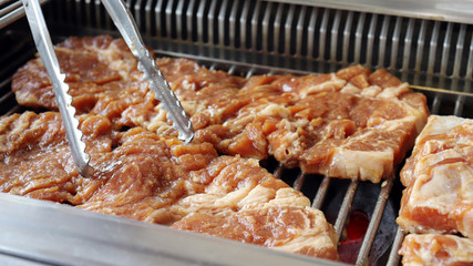 Roast meat using tongs. 