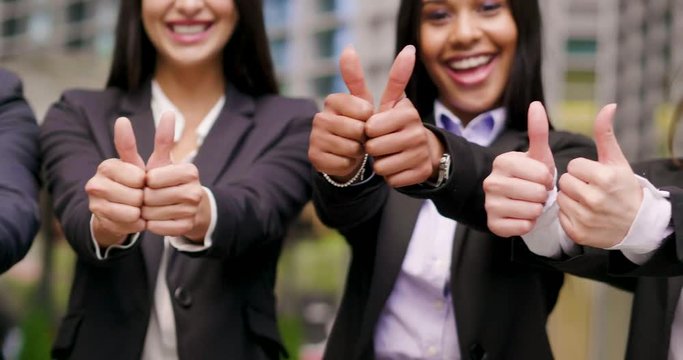 Business people of different ethnicities dressed in suits and ties, smile and "ok" raising their thumbs to celebrate the team's success. Concept of: internationality and career, cooperation.