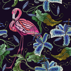 Obraz premium Embroidery flamingo and violet orchid flowers tropical seamless pattern. Fashionable embroidery pink flamingos, tropical summer background. Template for design of clothes