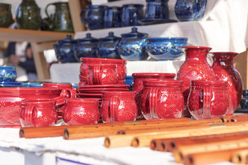 Ceramic mugs and pots, wooden whistles, wooden musical instruments, street market, goods displayed on the table.