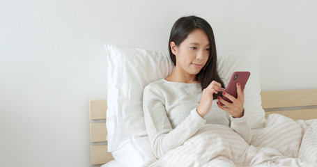 Woman sending sms on bed