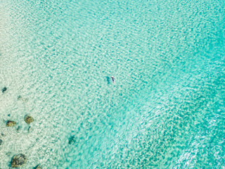 An aerial view of a surfer paddling in blue water on Queensland's Gold Coast in Australia