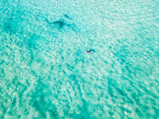 Fototapeta na wymiar An aerial view of a surfer paddling in blue water on Queensland's Gold Coast in Australia