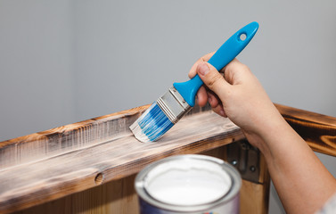 Housewife paints a wooden table with a brush
