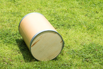 Wooden cylindrical tank on green lawn.