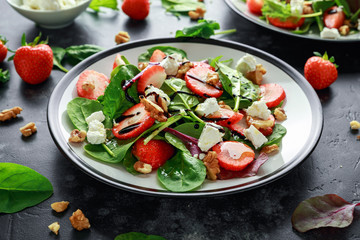 Summer Fruit Strawberry, spinach Salad with walnut, feta cheese balsamic vinegar, kale. in a plate. concepts health food