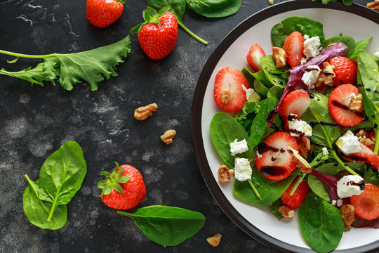 Summer Fruit Strawberry, spinach Salad with walnut, feta cheese balsamic vinegar, kale. in a plate. concepts health food