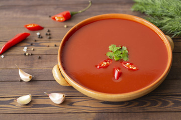 Spicy tomato soup on a wooden table, top view
