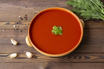 Spicy tomato soup on a wooden table, top view