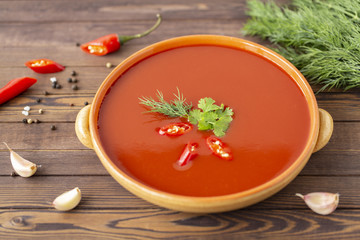 Spicy tomato soup on a wooden table, top view