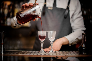 Barman pouring fresh summer Arnaud cocktail into the glasses