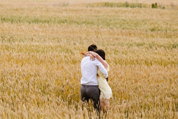 Naklejka na ściany i meble Long-awaited meeting of two lovers in the wheat field at sunset