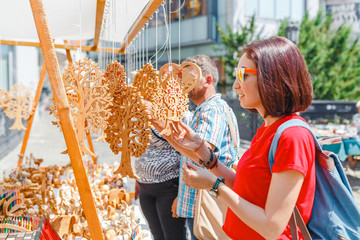 A woman tourist at a souvenir fair choosing handmade decorative woodcarving gifts