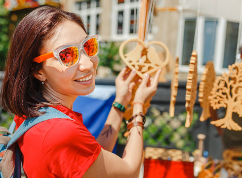 A woman tourist at a souvenir fair choosing handmade decorative woodcarving gifts