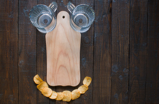 Funny Table Setting. Chips, Beer Mugs And A Wooden Board For Appetizers, On A Wooden Brown Table.