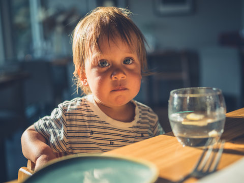 Little toddler at table in restaurant