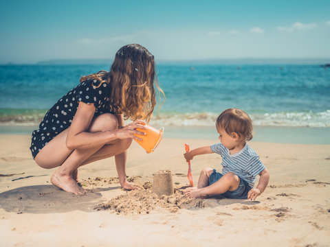 Young mother playing with son on beach