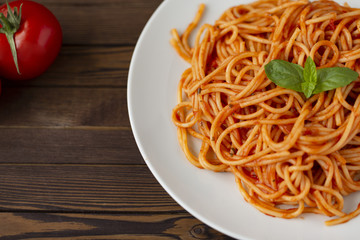 Spaghetti with tomato sauce in the dish on the wooden table