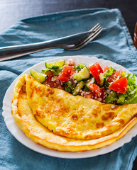 Omelet with vegetable salad in white plate on table