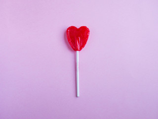 Red heart lollipop on pink background