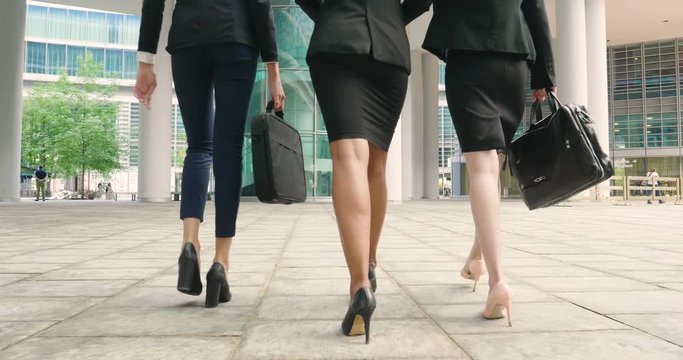 A business women of different ethnicities, in suit and high-heeled shoes, walk to the office while they talk about work, economics and financial budgets.