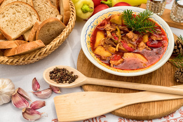 Pot goulash with divas placed on the table of ingredients - meat, pepper, tomato, spices, potatoes, garlic, onion recipe for the preparation of traditional European food