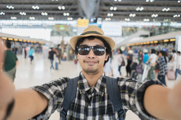 Asian man tourist taking a selfie with smart phone camera in airport.