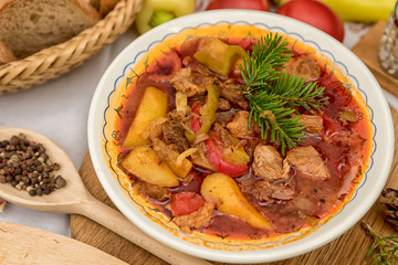 Pot goulash with divas placed on the table of ingredients - meat, pepper, tomato, spices, potatoes,...