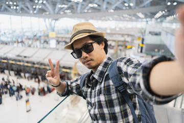 Asian man tourist taking a selfie with smart phone camera in airport.