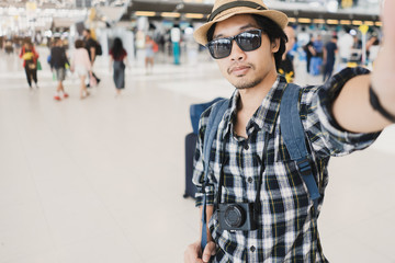 Asian man tourist taking a selfie with smart phone camera in airport.