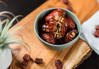 Red dates (jujube) stuffed with walnut in ceramic bowl on wooden board