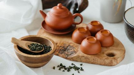 Chinese clay tea set with loose oolong green tea on wooden board