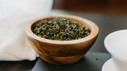 Fototapeta premium Loose oolong green tea leaves in wood bowl