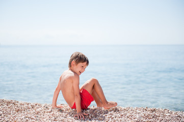 Fototapeta na wymiar beautiful healthy small child in shorts playing on sea beach on summer sunny day