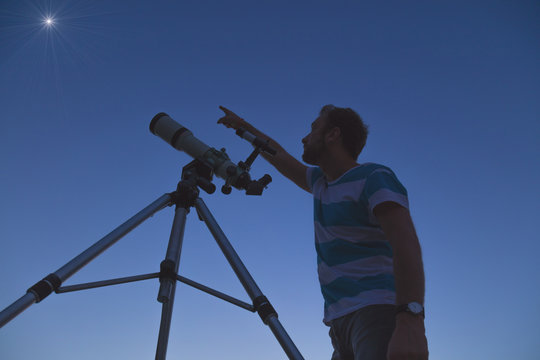 Man looking at the stars with a telescope.