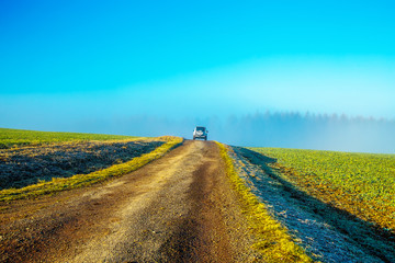 Obraz premium Beautiful field path with car in beautiful landscape.