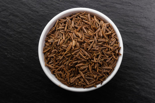 Seeds of cumin on a dark stone background