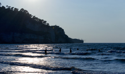 Silhouette of a group of people in backlit on the seaside having bath. For tourism and vacation...