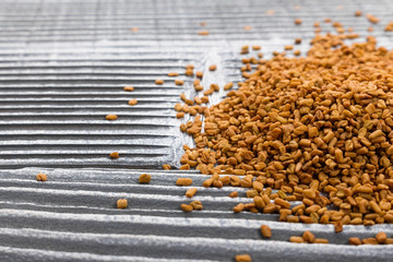 fragrant grains of fenugreek on a rustic background