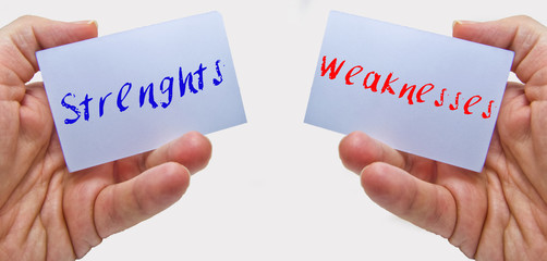 man hands holding cards with the words strenghts and weaknesses