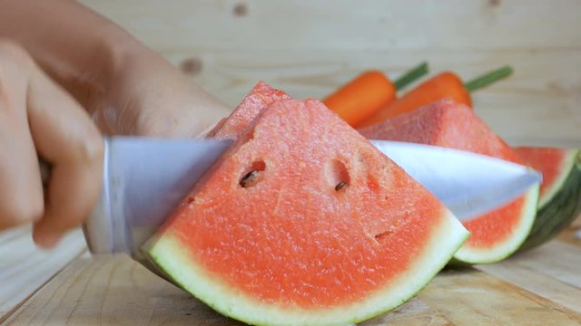 Close up shot hands of woman using kitchen knife to cut ripe watermelon on wooden cut board fresh  fruit for summer