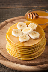 Fresh made delicious pancakes with banana, honey and maple syrup. Healthy morning breakfast concept.