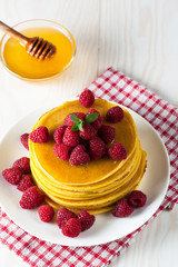 Fresh made delicious pancakes with berries, blackberries, raspberries, banana, honey and maple syrup. Healthy morning breakfast concept.