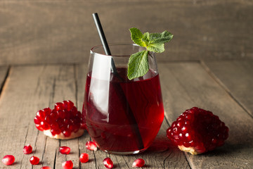 A glass of pomegranate juice with fresh pomegranate fruits on wooden table. Vitamins and minerals. Healthy drink concept.