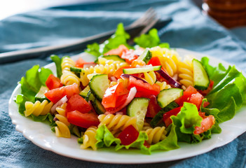 vegetables Pasta salad with tomato, lettuce, onion and cucumber in white plate on table